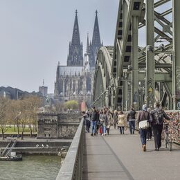 Menschen auf der Hohenzollernbrücke in Köln, im Hintergrund der Dom